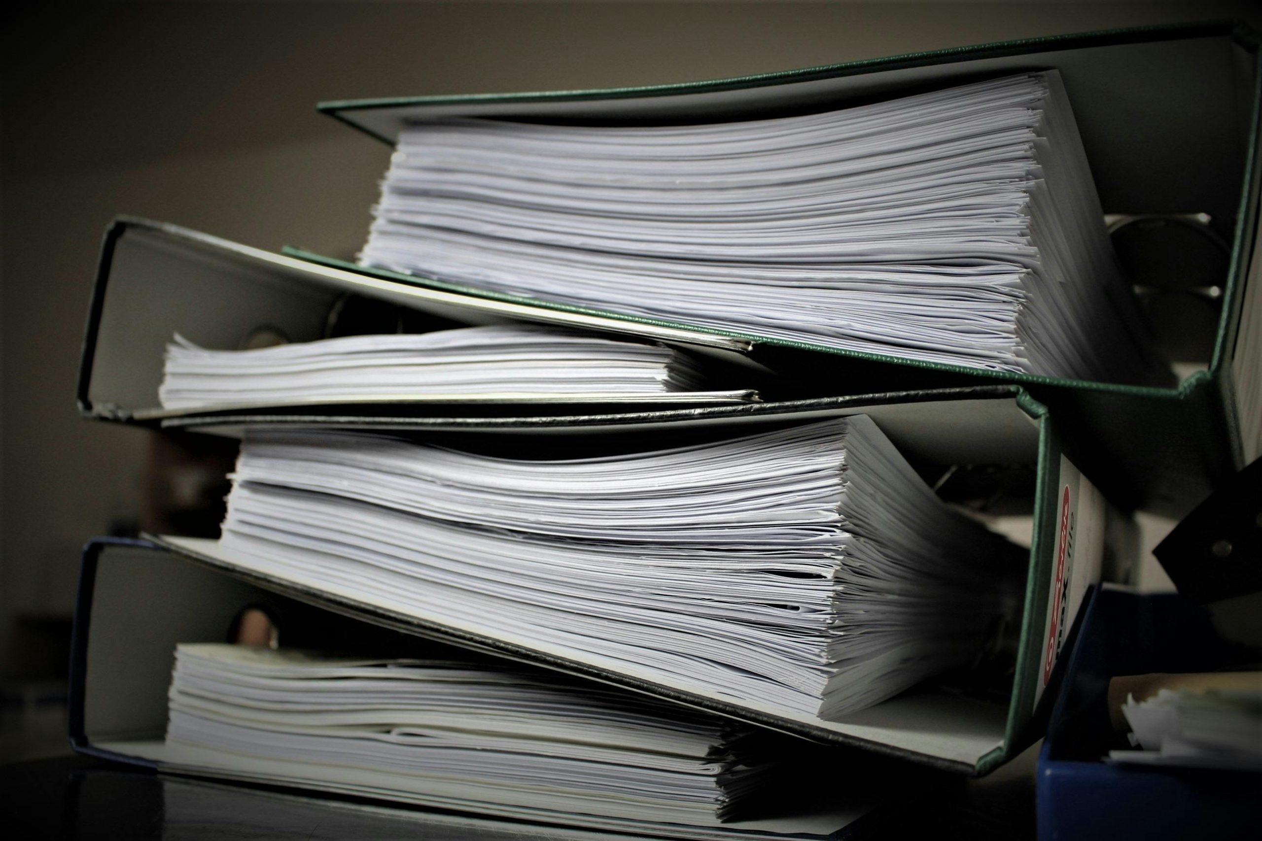 Photo of a stack of thick binders full of paper.