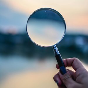Hand holding a magnifying glass outdoors