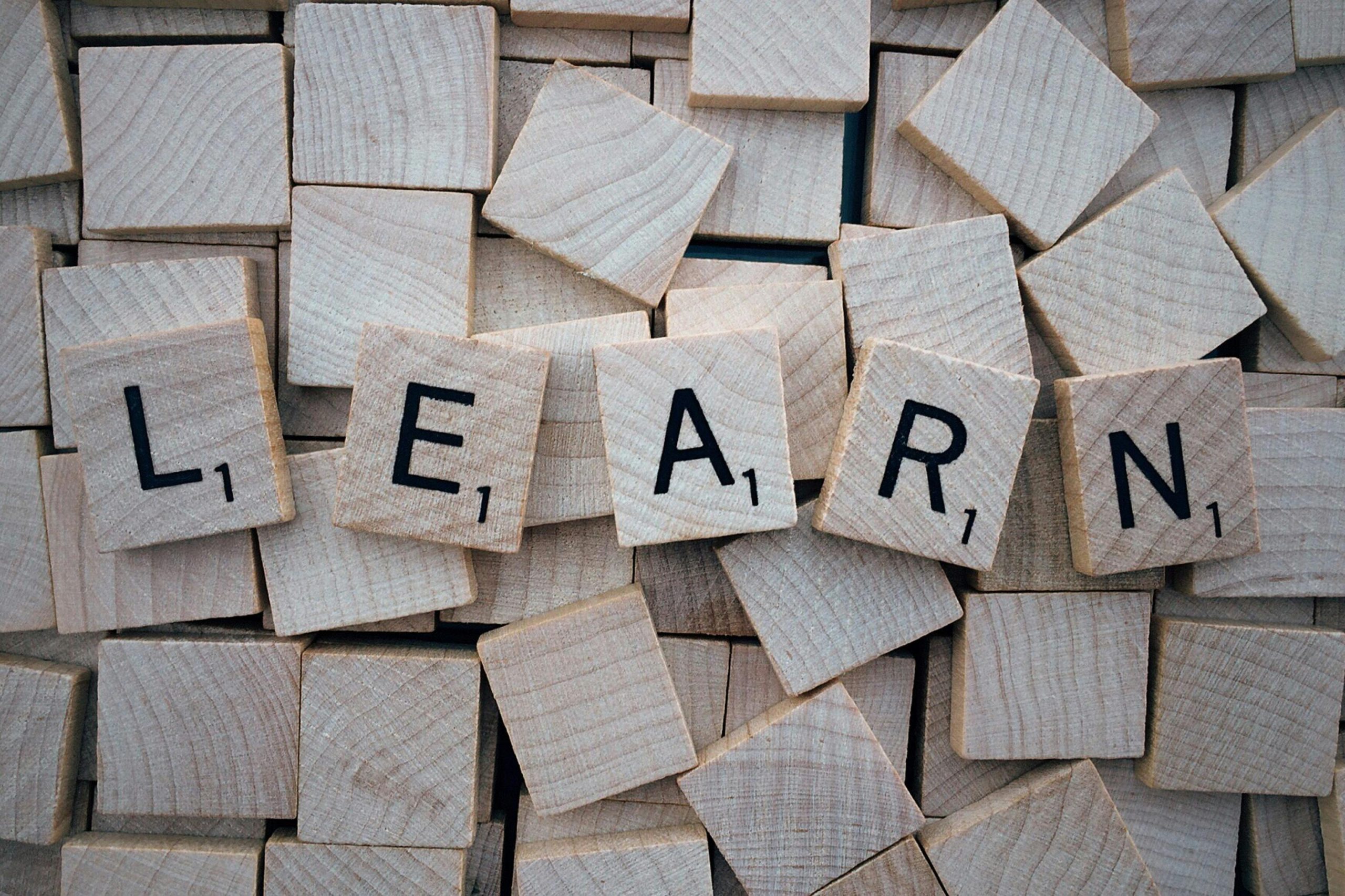 Scrabble tiles scattered on a surface, with five tiles spelling 'LEARN' in the center.