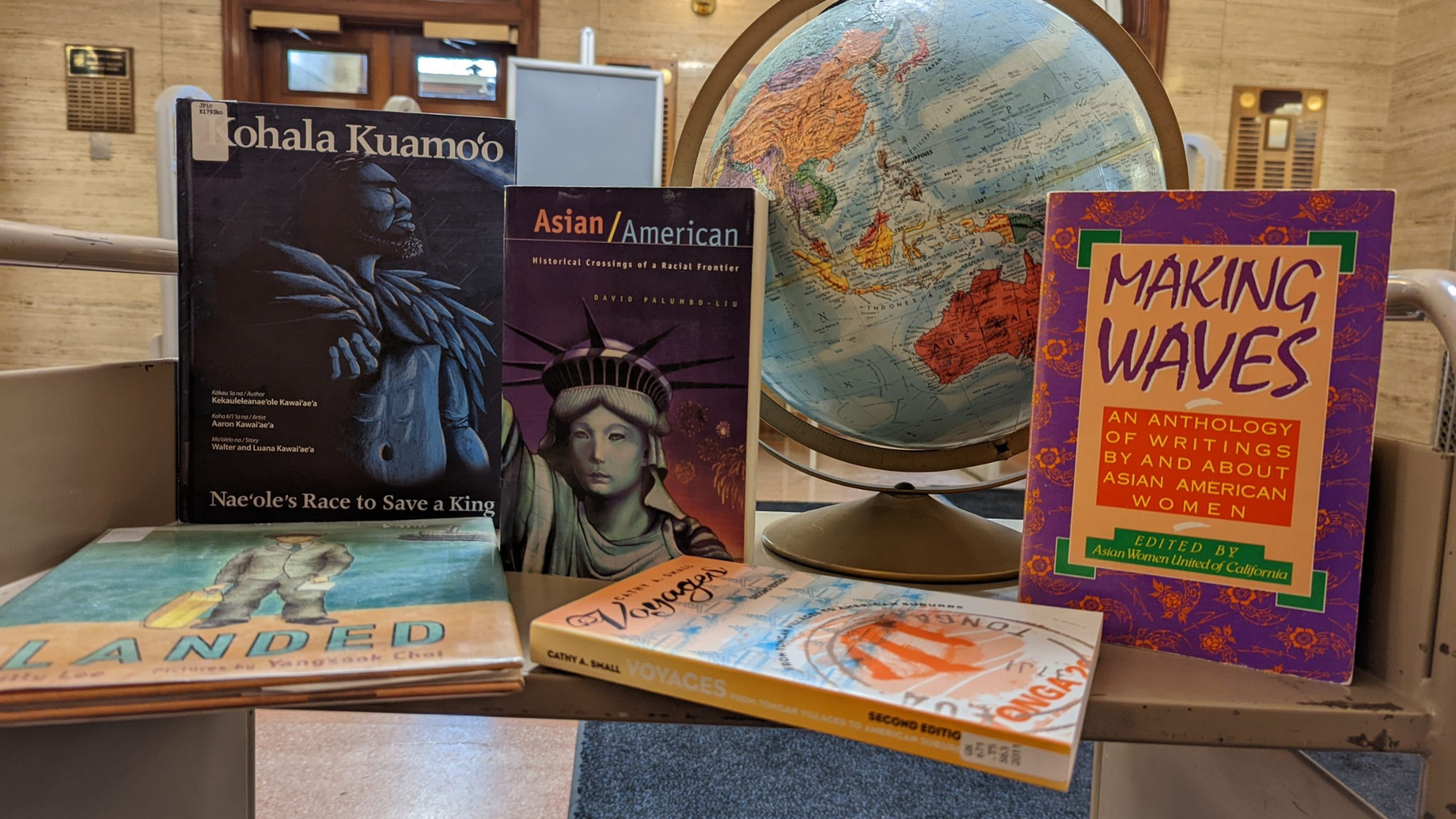 Display of books and a globe celebrating Asian American & Pacific Islander Heritage Month, with featured titles about Asian American history and literature.