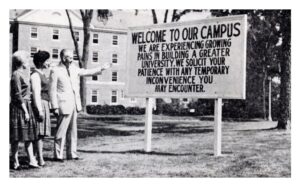 A campus sign from 1962 that reads, Welcome to our campus, we are experiencing growing pains in building a greater university. We solicit your patience with any temporary inconvenience you may encounter.