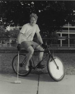 A young man on a bicycle holding a mallet